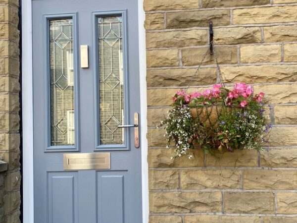 Contemporary composite door with full-length glazing and black furniture fitted to a UK home
